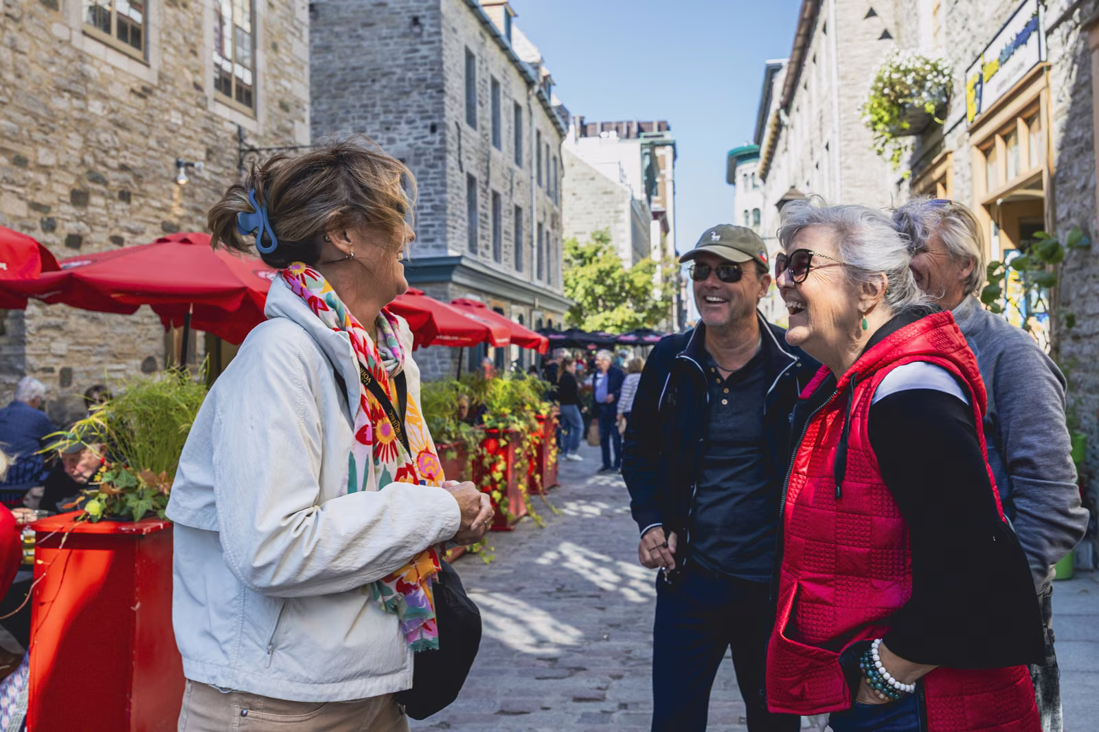 Des visiteurs rient ensemble dans une rue du Petit-Champlain, audioguides sur les oreilles.