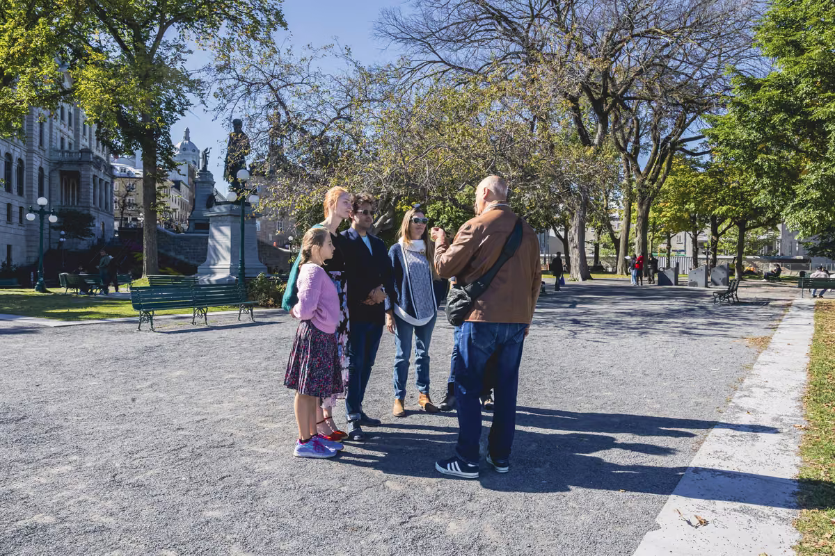 A guide and his group in a park of Old Québec on a sunny day.