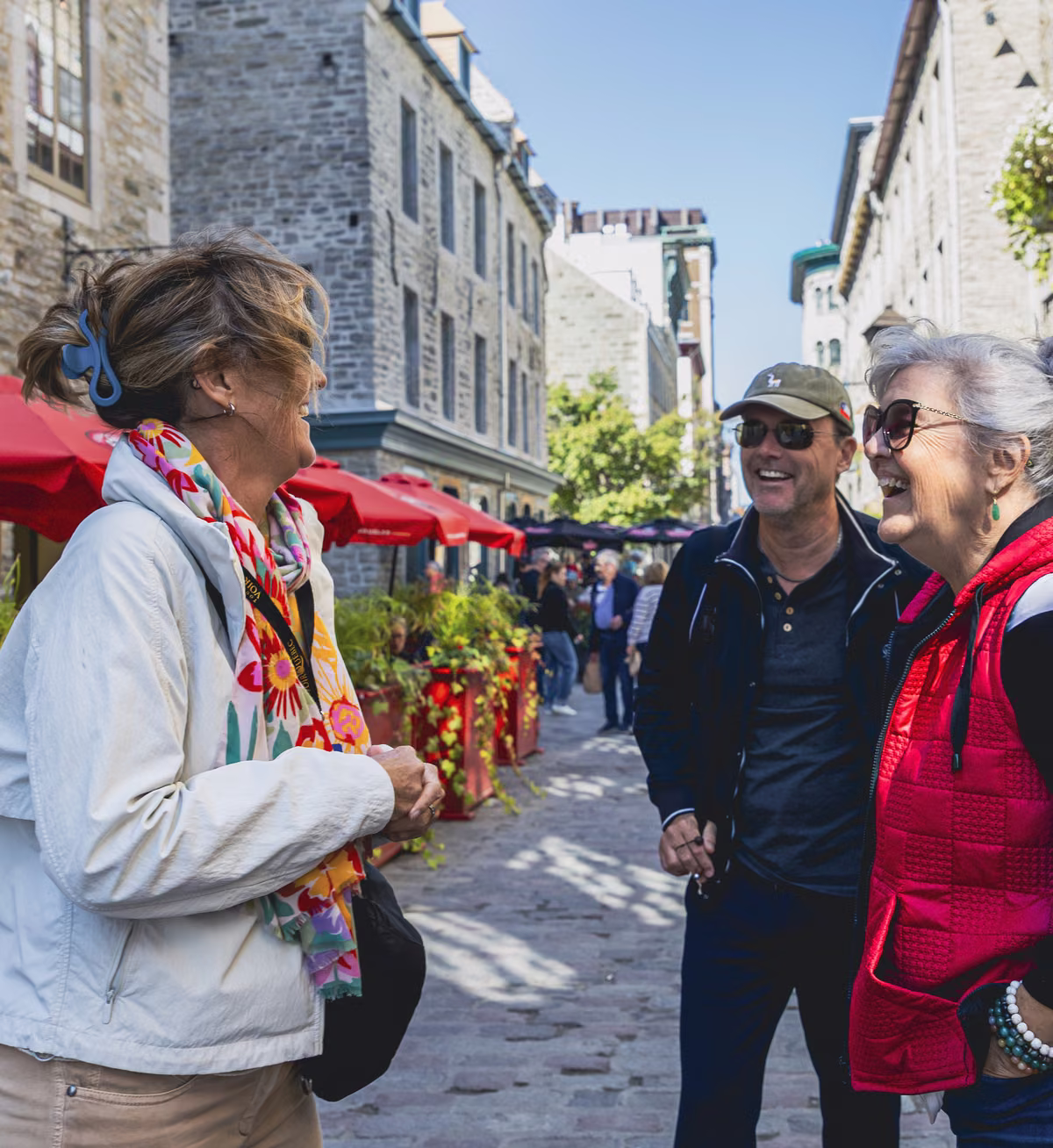 Une guide rit avec son groupe sous les parasols rouges de la basse-ville.